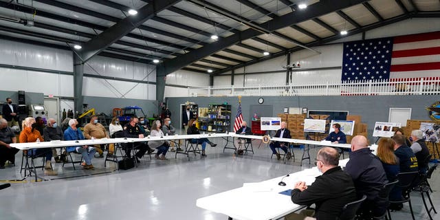 President Joe Biden attends a briefing from local leaders on the storm damage from tornadoes and extreme weather at Mayfield Graves County Airport in Mayfield, Ky., Wednesday, Dec. 15, 2021. Homeland Security Secretary Alejandro Mayorkas and Kentucky Gov. Andy Beshear are seated next to Biden. 