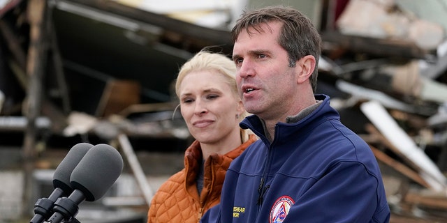 Kentucky Gov. Andy Beshear, accompanied by wife Britainy Beshear, speaks after surveying storm damage from tornadoes and extreme weather in Dawson Springs, Kentucky, Dec. 15, 2021. 