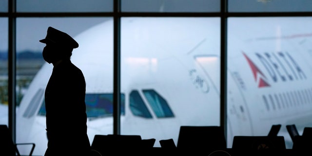 FILE - A Delta Airlines pilot wears a face mask as he walks through a terminal at Hartsfield-Jackson International Airport in Atlanta.