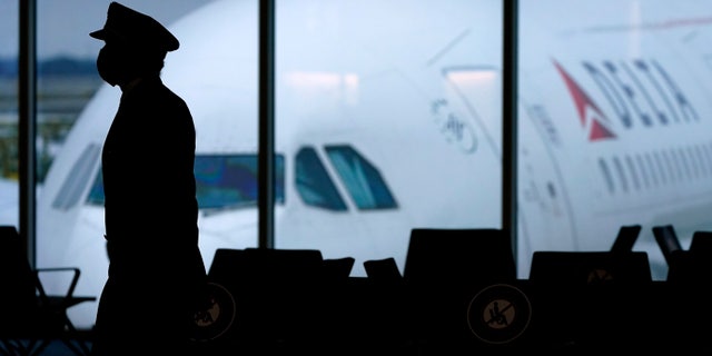 FILE - A Delta Airlines pilot wears a face mask as he walks through a terminal at Hartsfield-Jackson International Airport in Atlanta.