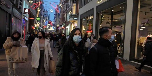 People walk down a street in Amsterdam, the Netherlands, Saturday, Dec. 18, 2021. (AP Photo/Peter Dejong)