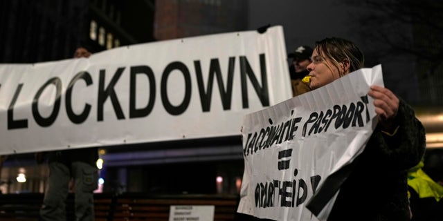 A protestor holds a banner during a small anti-COVID restriction demonstration in The Hague in the Netherlands, Saturday, Dec. 18, 2021. 