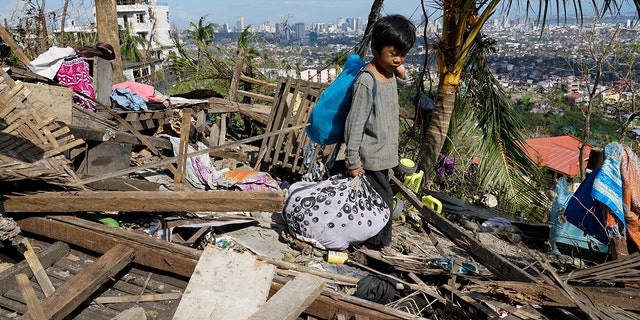Romel Lo-ang recovers personal belongings from their damaged home due to Typhoon Rai in Cebu province, central Philippines on Sunday Dec. 19, 2021. 
