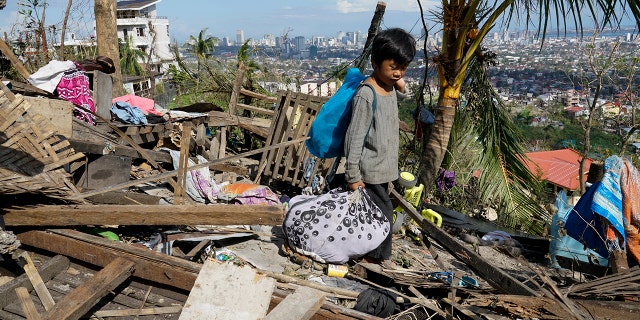 Romel Lo-ang recovers personal belongings from their damaged home due to Typhoon Rai in Cebu province, central Philippines on Sunday Dec. 19, 2021.