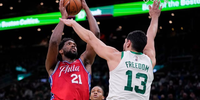 Philadelphia 76ers center Joel Embiid (21) shoots over Boston Celtics center Enes Freedom (13) during the second half of an NBA basketball game, Monday, Dec. 20, 2021, in Boston.