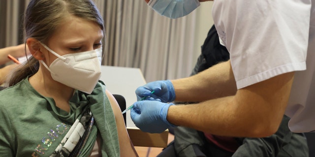 9-year-old Emma from Weimar is vaccinated with the Biontech vaccine at the Christmas vaccination for children and adults in Erfurt, Germany, Tuesday, Dec.21, 2021. (Bodo Schackow/dpa via AP)