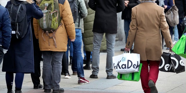 Menschen zeigen sich in der ersten Reihe des berühmten KaDeWe (Kaufhaus des Westens', Dienstag, 21. Dezember 2021) in Berlin.  (AP-Foto / Michael Sohn)