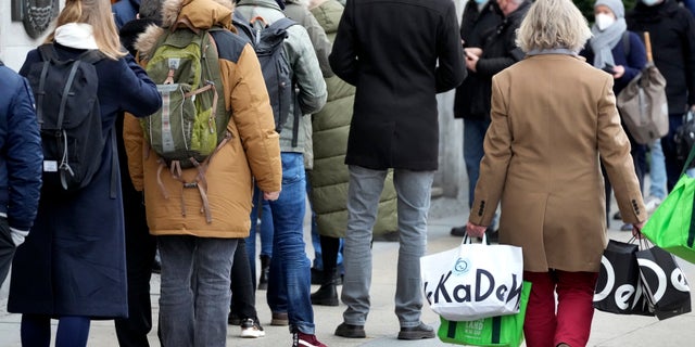 People present their vaccination status as they queue in front of the famous department store 'KaDeWe' (Department Store Of The West' in Berlin, Germany, Tuesday, Dec. 21, 2021. (AP Photo/Michael Sohn)