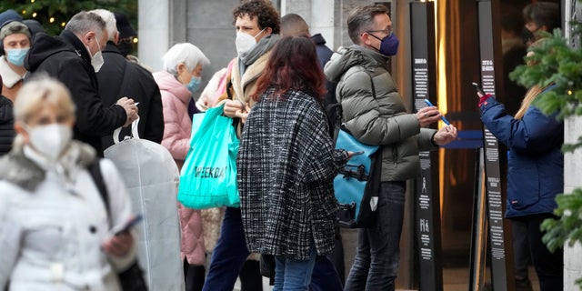 People present their vaccination status as they queue in front of the famous department store 'KaDeWe' (Department Store Of The West') in Berlin, Germany, Tuesday, Dec. 21, 2021. (AP Photo/Michael Sohn)