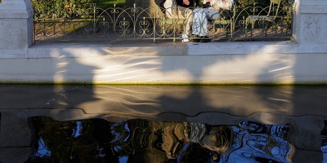 Les gens prennent le soleil dans le jardin du Luxembourg à côté du Sénat français, à Paris, France, le mardi 21 décembre 2021. (AP Photo/Francois Mori)