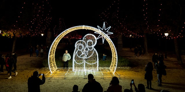 People pose for snapshots in front of Christmas decorations in El Retiro park in Madrid, Spain, Tuesday, Dec. 21, 2021. (AP Photo/Bernat Armangue)