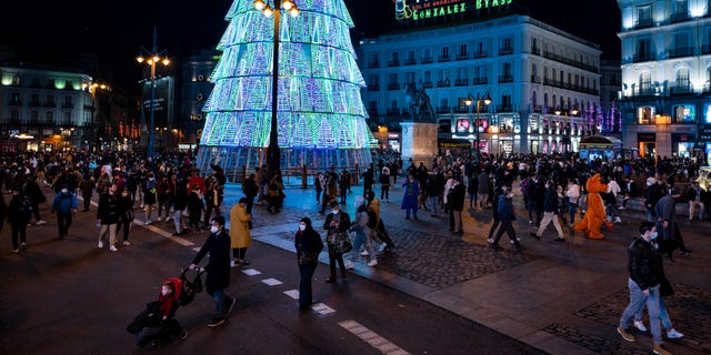 People walk along Sol square in downtown Madrid, Spain, Tuesday, Dec. 21, 2021. (AP Photo/Bernat Armangue)