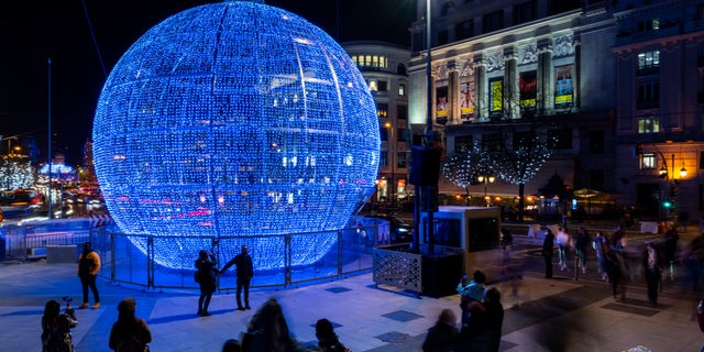 People walk past Christmas lights in downtown Madrid, Spain, Tuesday, Dec. 21, 2021. (AP Photo/Bernat Armangue)