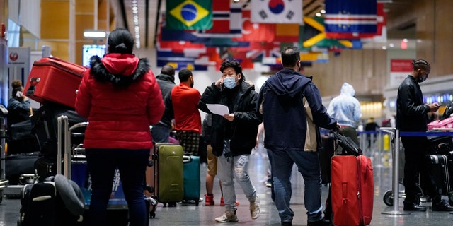 Travelers wait in line to check in for flights at Logan Airport, Tuesday, Dec. 21, 2021, in Boston.  