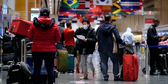Travelers wait in line to check in for flights at Logan Airport, Tuesday, Dec. 21, 2021, in Boston.