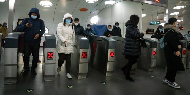Los viajeros que usan máscaras faciales para protegerse del COVID-19 salen de una estación de metro en el distrito comercial central de Beijing el jueves 23 de diciembre de 2021 (AP Photo / Mark Schiefelbein).