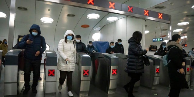 Commuters wearing face masks to protect against COVID-19 exit a subway station in the central business district in Beijing, Thursday, Dec. 23, 2021. (AP Photo/Mark Schiefelbein)