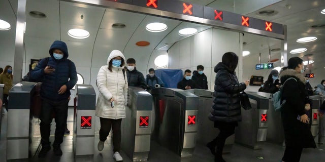 Los viajeros que usan máscaras faciales para protegerse del COVID-19 salen de una estación de metro en el distrito comercial central de Beijing el jueves 23 de diciembre de 2021 (AP Photo / Mark Schiefelbein).