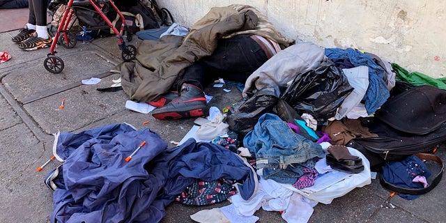 La gente duerme cerca de ropa desechada y agujas usadas en una calle del vecindario Tenderloin en San Francisco, el 25 de julio de 2019. 