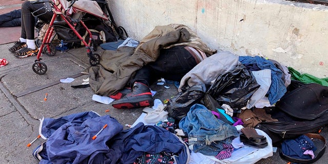 People sleep near discarded clothing and used needles on a street in the Tenderloin neighborhood in San Francisco, on July 25, 2019. 