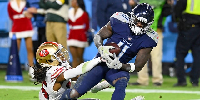 Le receveur large des Titans du Tennessee AJ Brown (11) attrape une passe de touché alors qu'il est défendu par le demi de coin des 49ers de San Francisco Josh Norman, à gauche, dans la seconde moitié d'un match de football de la NFL le jeudi 23 décembre 2021 à Nashville, Tennessee.