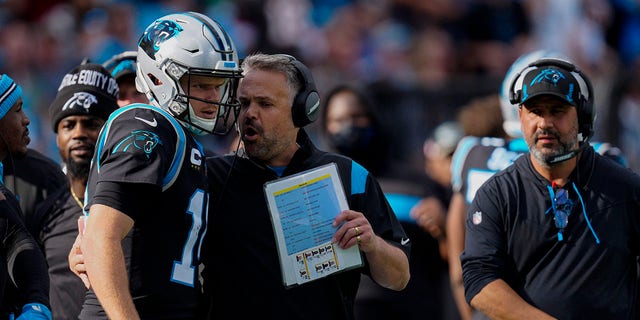 Carolina Panthers head coach Matt Rhule talks with quarterback Sam Darnold during the first half of a game against the Tampa Bay Buccaneers on December 26, 2021 in Charlotte, NC.