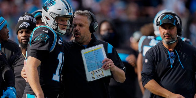 Carolina Panthers head coach Matt Rhule talks with quarterback Sam Darnold during the first half of a game against the Tampa Bay Buccaneers on December 26, 2021 in Charlotte, NC.