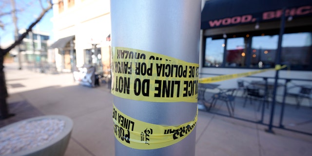 Leftover police tape is wrapped around a pole to block off the sidewalk by a pizza rlor Tuesday, Dec. 28, 2021 in Lakewood, Colo., Near one of the scenes of a shooting spree that left five people dead — including the suspected shooter Monday evening — and left three more people wounded.