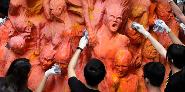 University students clean the "Pillar of Shame" statue, a memorial for those killed in the 1989 Tiananmen crackdown, at the University of Hong Kong, June 4, 2019. (AP Photo/Kin Cheung, File)