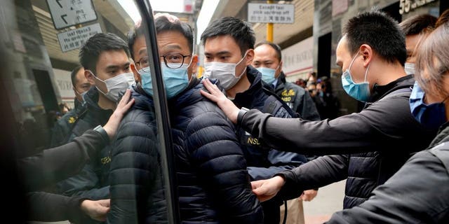 Editor of Stand News' Patrick Lam, center, is escorted by police officers into a van after they searched evidence at his office in Hong Kong, Wednesday, Dec. 29, 2021. Hong Kong police raided the office of the online news outlet on Wednesday after arresting several people for conspiracy to publish a seditious publication.