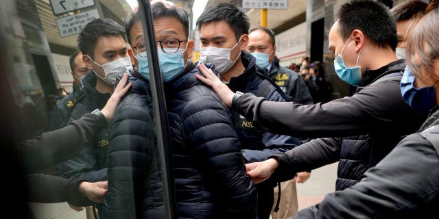 Editor of Stand News' Patrick Lam, center, is escorted by police officers into a van after they searched evidence at his office in Hong Kong, Wednesday, Dec. 29, 2021. Hong Kong police raided the office of the online news outlet on Wednesday after arresting several people for conspiracy to publish a seditious publication.