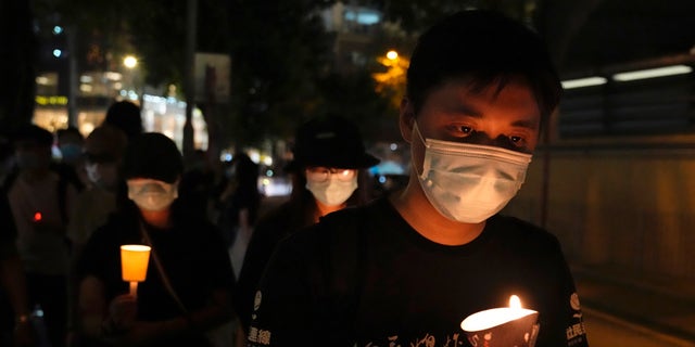 Ľudia kráčajú so sviečkami, aby si pripomenuli výročie vojenského zásahu proti prodemokratickému študentskému hnutiu v Pekingu, mimo Victoria Park v Hong Kongu, piatok 4. júna 2021 (AP Photo/Kin Cheung, File)