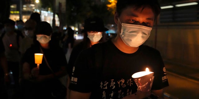 People walk with candles to mark the anniversary of the military crackdown on a pro-democracy student movement in Beijing, outside Victoria Park in Hong Kong, Friday, June 4, 2021. (AP Photo/Kin Cheung, File)