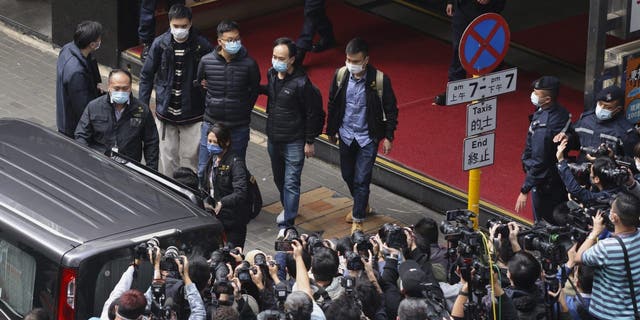 Editor of Stand News Patrick Lam, fourth from left, is escorted by police officers into a van after they searched for evidence at his office in Hong Kong, Wednesday, Dec. 29, 2021. 