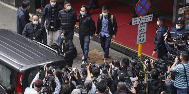 Editor of Stand News Patrick Lam, fourth from left, is escorted by police officers into a van after they searched for evidence at his office in Hong Kong, Wednesday, Dec. 29, 2021.