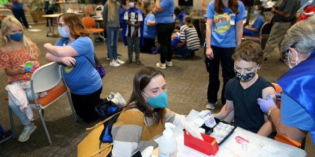 FILE - Retired registered nurse Jill Rill, right, puts a bandage on Jackson Stukus, 11, after he received a Pfizer COVID-19 vaccine as his mom Kristin looks on during the first COVID-19 vaccine clinic in Franklin County for children age 5-11 at Nationwide Children's Hospital in Columbus, Ohio, Nov. 3, 2021. (AP Photo/Paul Vernon, File)