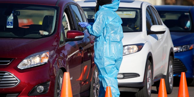 A medical technician performs a nasal swab test on a motorist queued up in a line at a COVID-19 testing site near All City Stadium, Thursday, Dec. 30, 2021, in southeast Denver. (AP Photo/David Zalubowski)