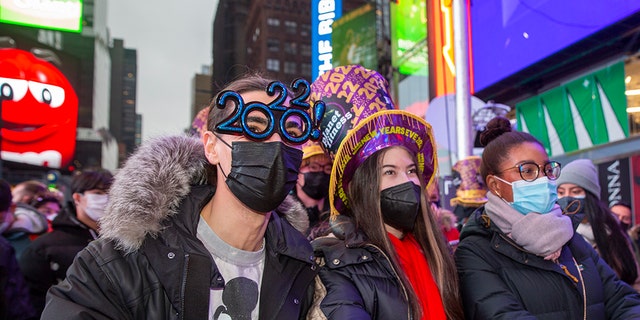 From left, Christopher Gicostanzo of Canada, Emma Marianni and Zoe Fauchi, both from Paris, France, stand in Times Square while waiting for the annual New Year's Eve ball drop in New York City on Friday, Dec. 31, 2021. 