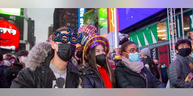 From left, Christopher Gicostanzo of Canada, Emma Marianni and Zoe Fauchi, both from Paris, France, stand in Times Square while waiting for the annual New Year's Eve ball drop in New York City on Friday, Dec. 31, 2021.
