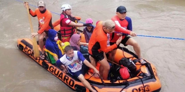 In this handout photo provided by the Philippine Coast Guard, residents ride a rubber boat along floods caused by Typhoon Rai as they are evacuated to higher grounds in Cagayan de Oro City, southern Philippines on Thursday, Dec. 16, 2021. 