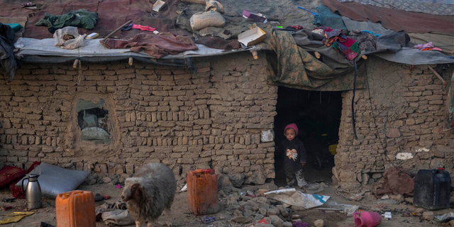 A child looks out of the doorway of his home in a neighborhood where many internally displaced people have been living for years, in Kabul, Afghanistan, Tuesday, Dec. 7, 2021.