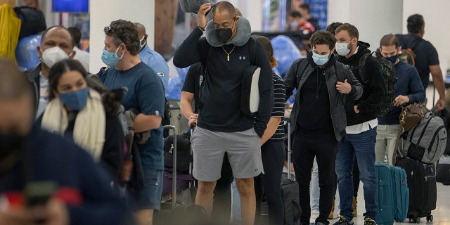 Travelers make their way through Miami International Airport on Dec. 23, 2021, in Miami. U.S. holiday travel numbers are rivaling 2019 amid an omicron variant surge, and President Biden is rescinding his travel ban on eight African countries where the variant first spread. (Photo by Joe Raedle/Getty Images)
