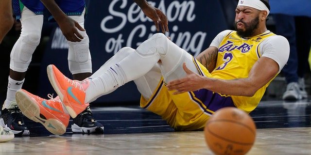 Los Angeles Lakers forward Anthony Davis (3) holds his leg after falling in the third quarter of a game against the Minnesota Timberwolves Friday, Dec. 17, 2021, in Minneapolis. The Timberwolves won 110-92.