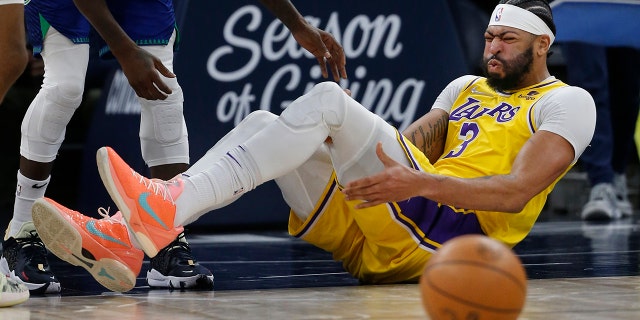 Los Angeles Lakers forward Anthony Davis (3) holds his leg after falling in the third quarter of a game against the Minnesota Timberwolves Friday, Dec. 17, 2021, in Minneapolis. The Timberwolves won 110-92.