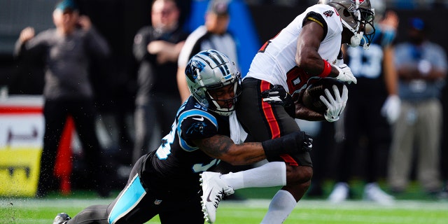 Tampa Bay Buccaneers wide receiver Antonio Brown is tackled by Carolina Panthers defensive back Myles Hartsfield during the first half of an NFL football game Sunday, Dec. 26, 2021, in Charlotte, N.C.