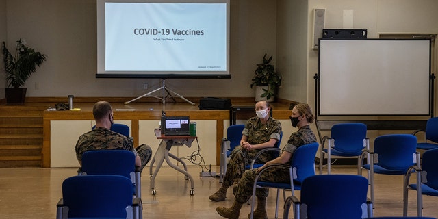 United States Marine Corp Gunnery Sergeant talks with US Navy medical officers about issues surrounding the coronavirus vaccine, at Camp Foster on April 28, 2021, in Ginowan, Japan. 