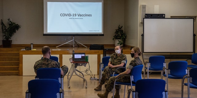 United States Marine Corp Gunnery Sergeant talks with US Navy medical officers about issues surrounding the coronavirus vaccine, at Camp Foster on April 28, 2021, in Ginowan, Japan.