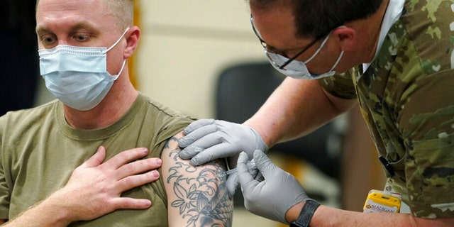 FILE - Staff Sgt. Travis Snyder, left, receives the first dose of the Pfizer COVID-19 vaccine. (AP Photo/Ted S. Warren, File) 
