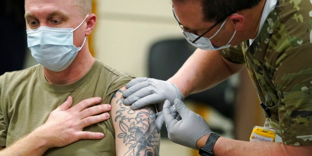 FILE - Staff Sgt. Travis Snyder, left, receives the first dose of the Pfizer COVID-19 vaccine given at Madigan Army Medical Center at Joint Base Lewis-McChord in Washington state, Dec. 16, 2020, south of Seattle. The Army says 98% of its active duty force had gotten at least one dose of the mandatory coronavirus vaccine as of this week’s deadline for the shots. (AP Photo/Ted S. Warren, File) 