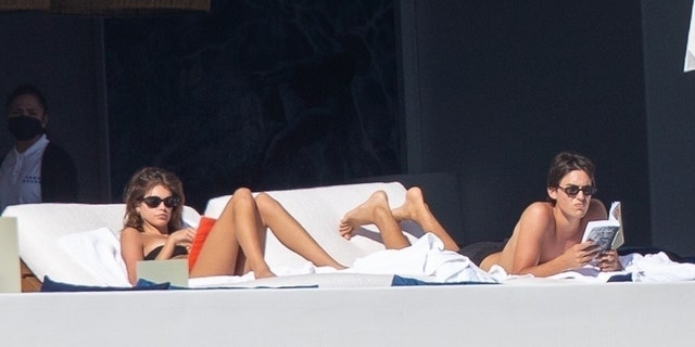 Kaia Gerber lounged next two a young unidentified guy who was reading a book. 